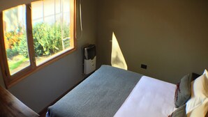 Un dormitorio con una cama, una ventana y un calentador.