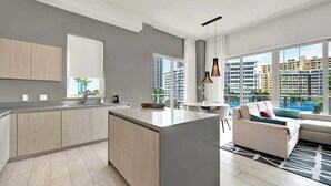 Eine moderne Wohnung mit Küche, Essbereich und Wohnzimmer, ausgestattet mit großen Fenstern und Blick auf die Stadt.