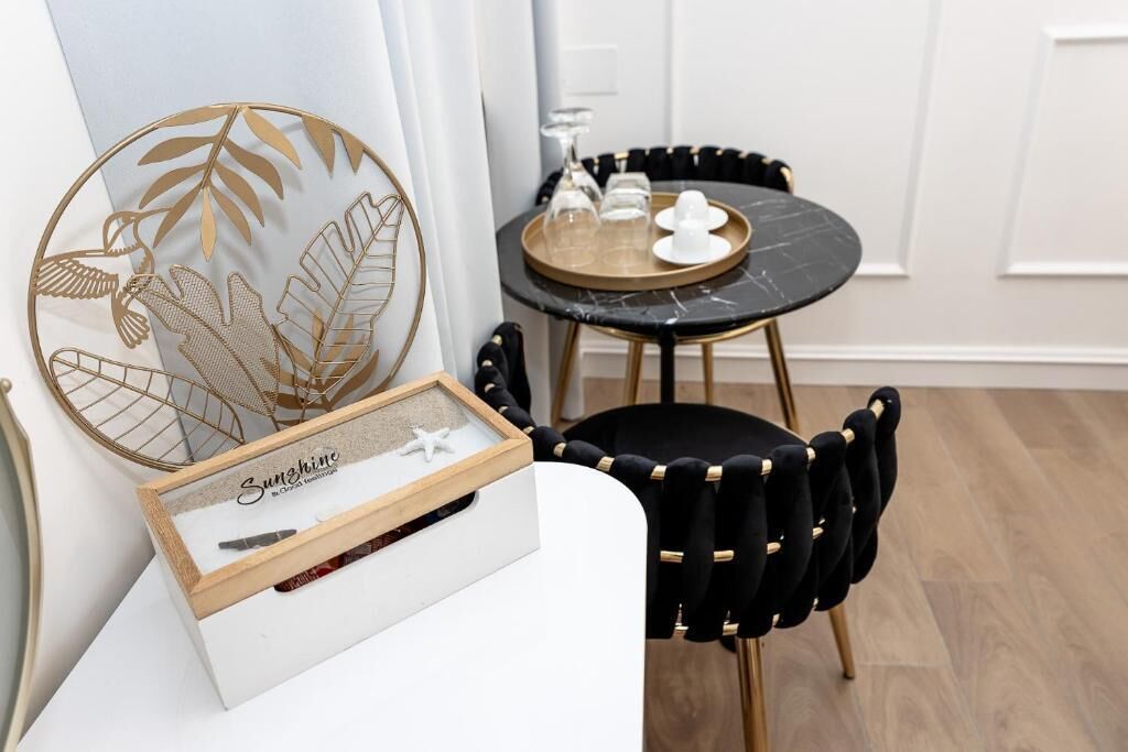 A dining area with a round table, black chairs, and a decorative wall piece.