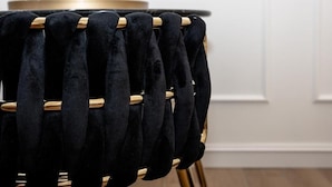 A black velvet chair with a wooden frame and a gold-colored base.