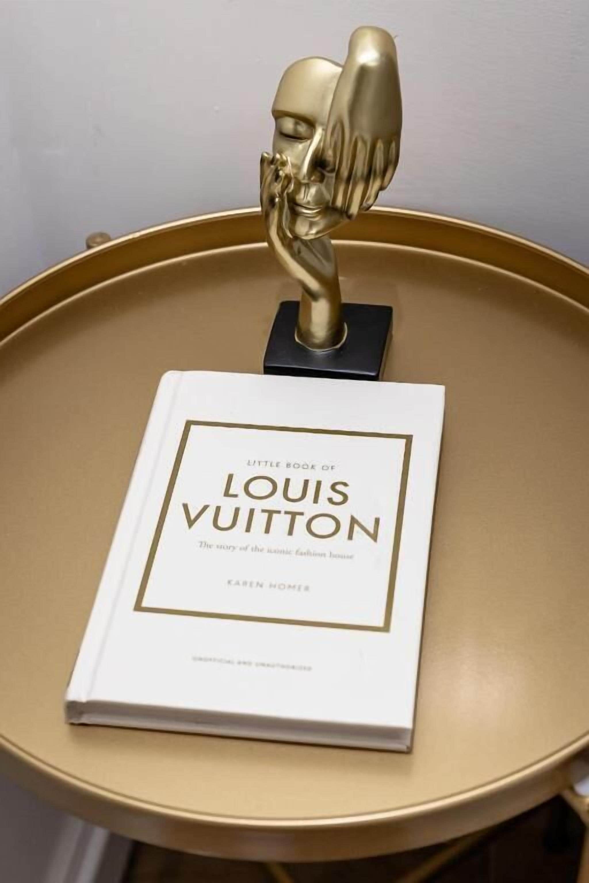 Un libro intitolato 'Little Book of Louis Vuitton' su un tavolo rotondo.