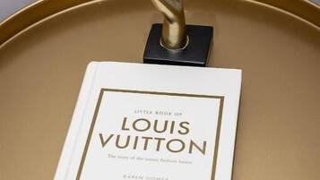 Un libro intitolato 'Little Book of Louis Vuitton' su un tavolo rotondo.