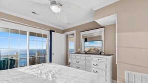 Ein Schlafzimmer mit einem großen Bett, einem Schminktisch, einem Deckenventilator und Meerblick.