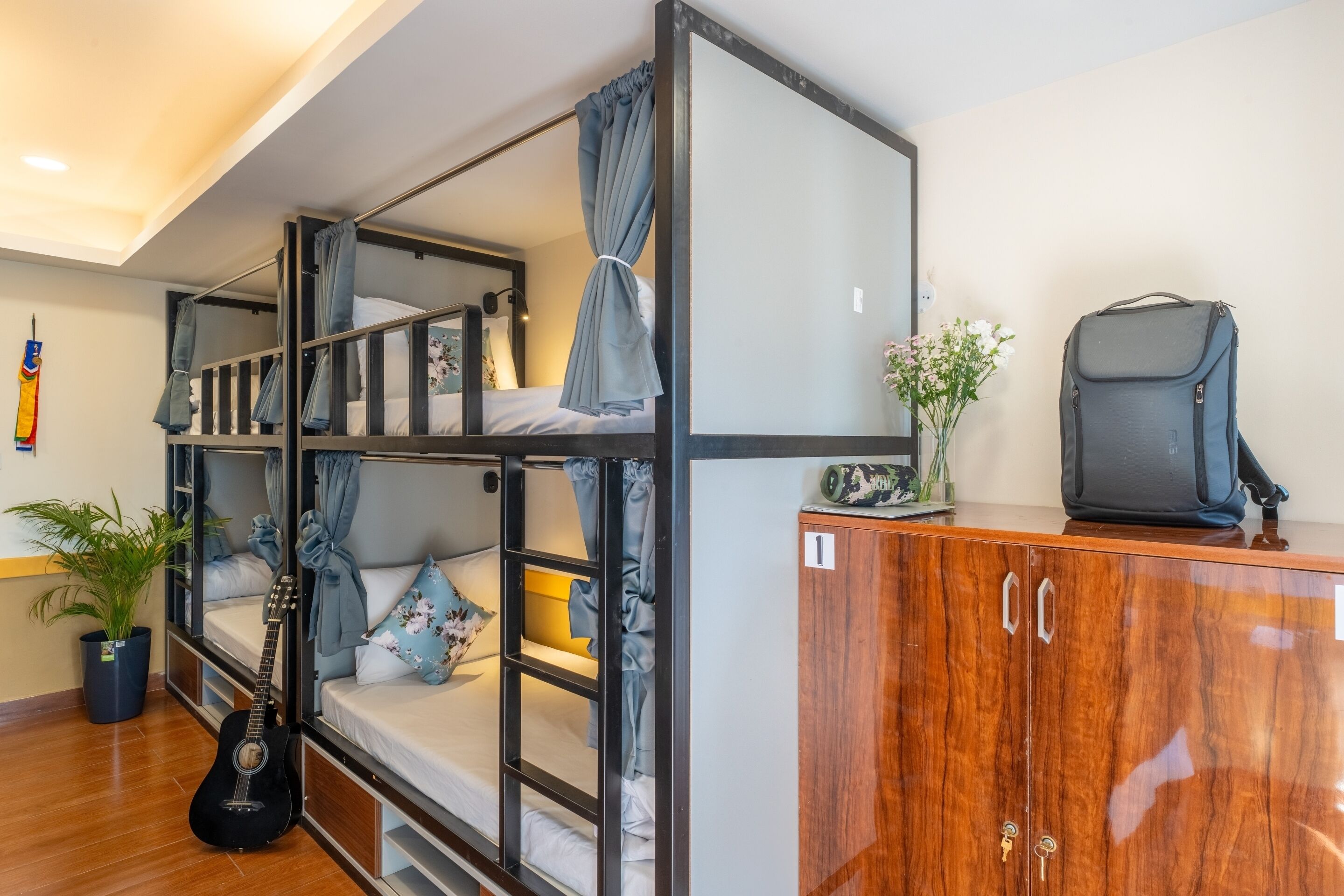 A bunk bed room with a guitar, a suitcase, and a cabinet.