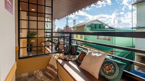 A balcony with a view of buildings and a crane, featuring a wooden ceiling and a tiled floor. - Moustache Hostel Gangtok (Gangtok)