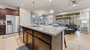 A modern kitchen with granite countertops, stainless steel appliances, and pendant lighting. - NEW Paradise Splash Villa! (Kissimmee)