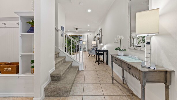 A clean, modern hallway with a staircase, a desk with a mirror, and a 'JUNK' box on the left. - NEW Paradise Splash Villa! (Kissimmee)