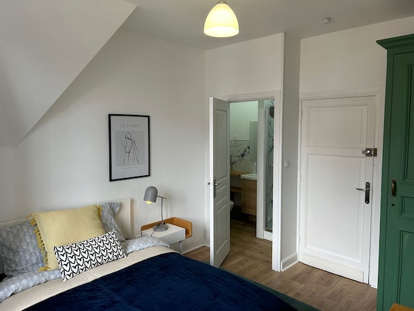 Une chambre à coucher avec un lit, une table de chevet, une lampe et un tableau encadré au mur.
