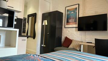 A bedroom with a bed, a TV, a wardrobe, and a mirror.