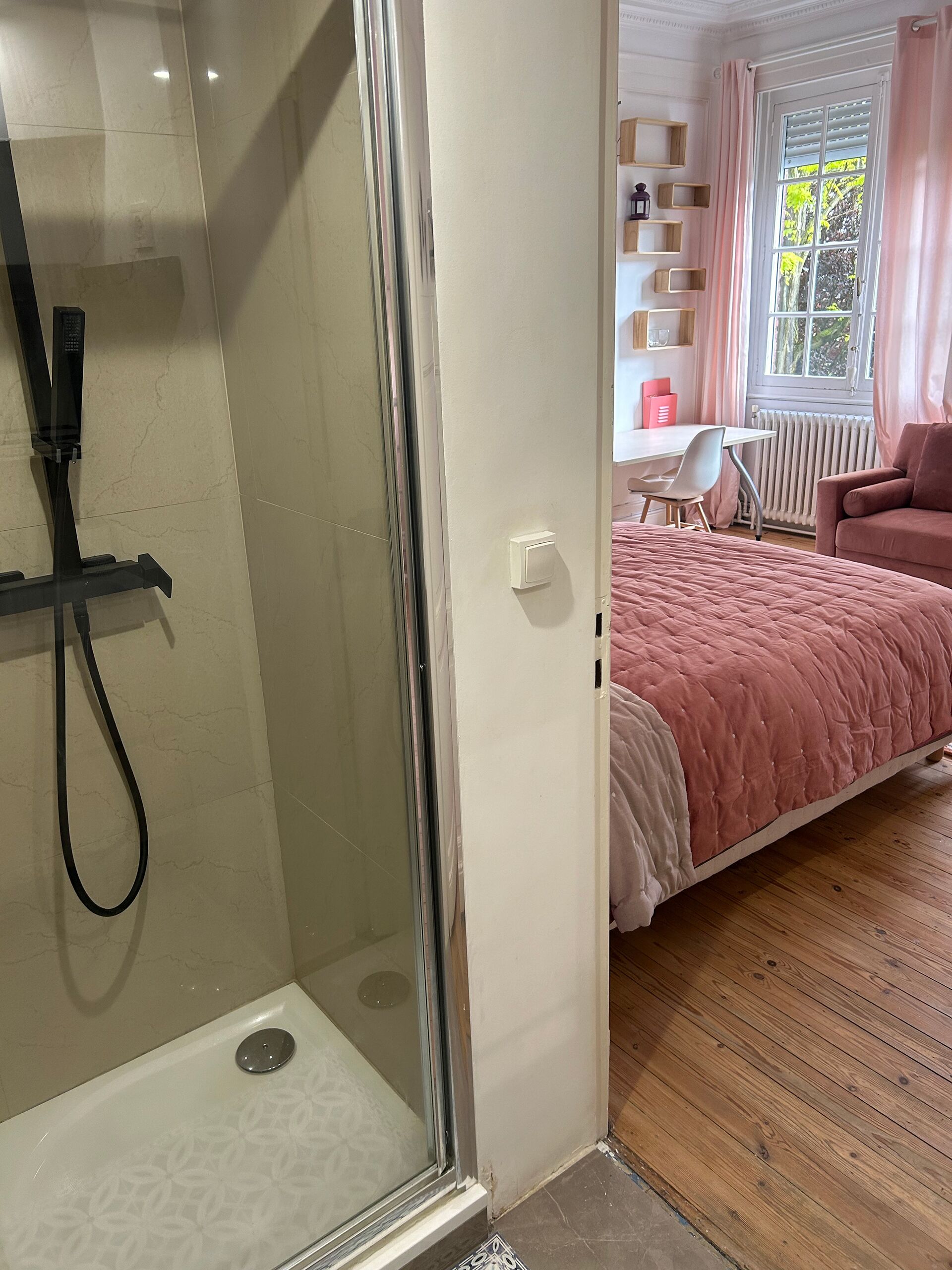 Un baño moderno con ducha de vidrio, lavamanos blanco y perchero.