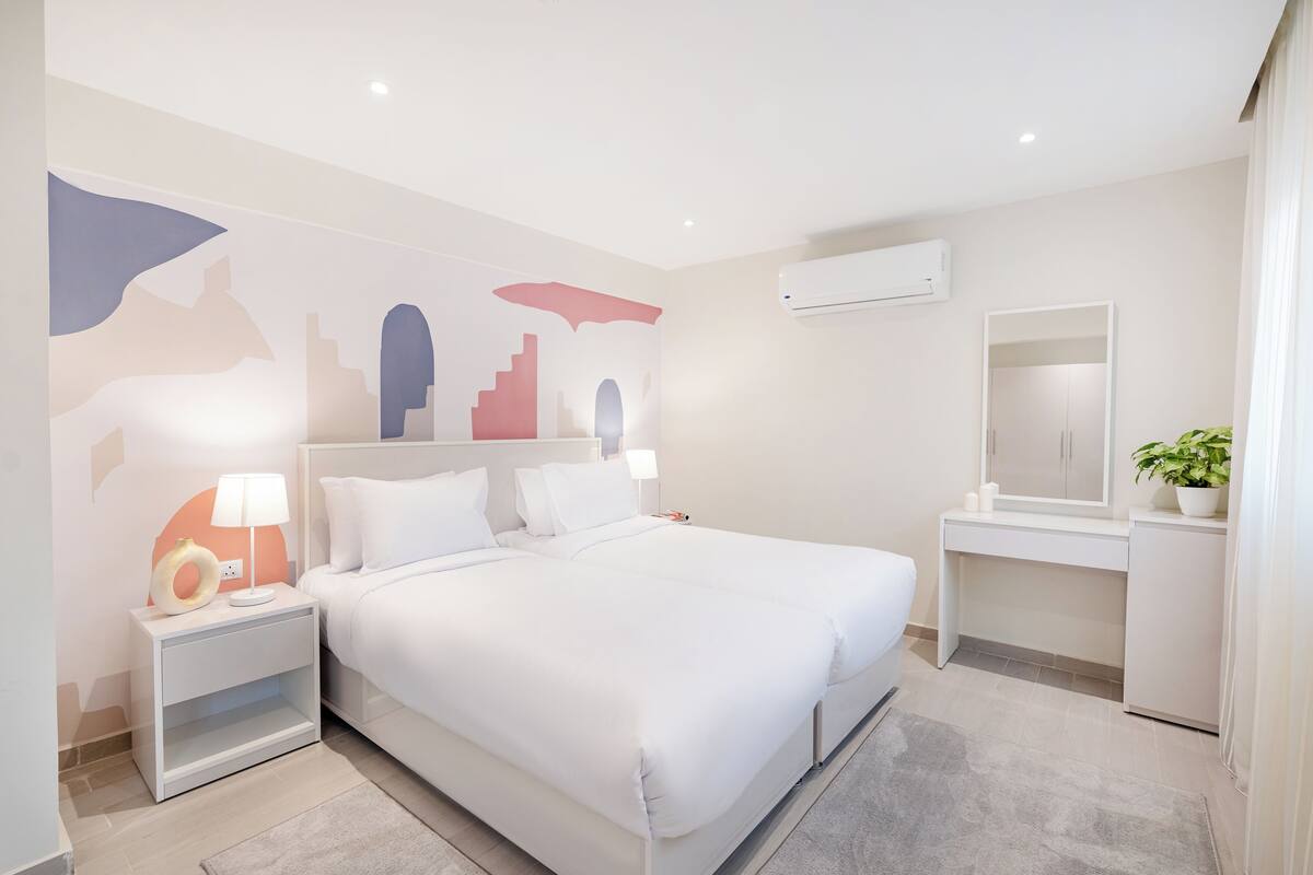 A modern hotel room with a large bed, a desk, and a mirror.