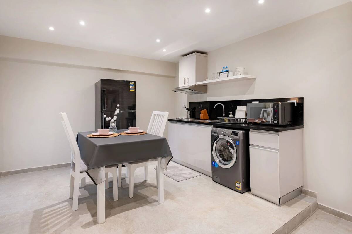 A compact kitchen with a washing machine, a coffee maker, and a microwave.