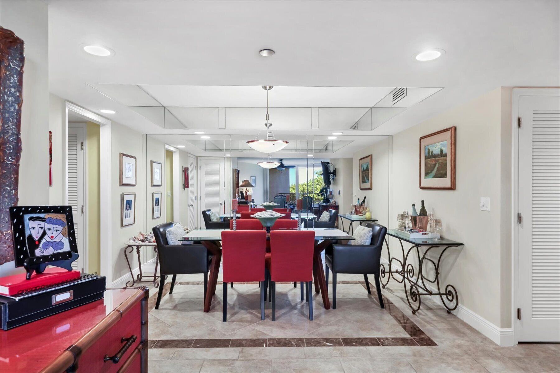 A dining area with a large table, red and black chairs, and a chandelier.