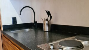 A kitchen with a black countertop, stainless steel stove, and wooden cabinets. - Private Jacuzzi with Pool  Studio S11 (Tulum)
