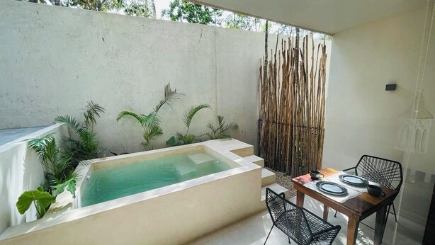 A spa area with a hot tub, a table with chairs, and a bamboo screen. - Private Jacuzzi with Pool  Studio S11 (Tulum)