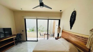 A hotel room with a bed, a desk, a chair, a TV, and a balcony with a table and chairs. - Private Jacuzzi with Pool  Studio S11 (Tulum)
