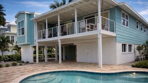 Ein zweistöckiges Haus mit überdachter Veranda und Swimmingpool.