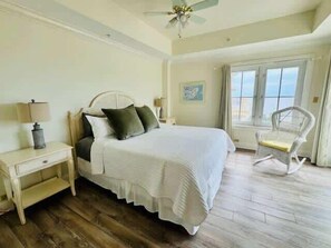 A bedroom with a bed, nightstands, a chair, and a window with curtains. - Seaside Villa- Oceanfront 3BDR with Golf Cart (Daufuskie Island)