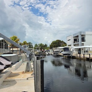 A marina with boats docked, a white building with balconies, and palm trees in the background. - Waterfront Getaway in Key Largo with 60-Foot Dock and Pool (Key Largo)