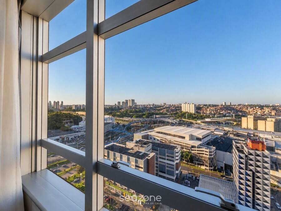 Um edifício alto com vista para o horizonte urbano através de grandes janelas.