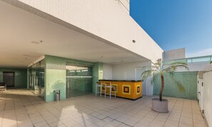 Um edifício moderno com entrada de vidro, balcão de recepção e um vaso com planta.