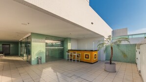 A modern building with a glass entrance, a reception desk, and a potted plant. - Your Complete Stay in a Building With Pool and Gym, 290m From Shopping da Bahia - Ibfs (Salvador)