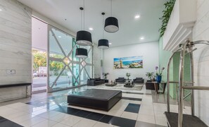 En moderne lobby med en sort lædersofa, et sofabord og et maleri af et kystlandskab.