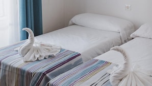 Twee enkele bedden met gestreepte lakens en witte handdoeken.