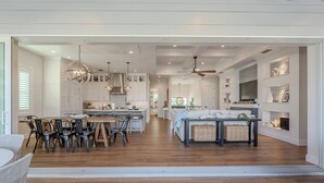 Een ruime keuken met moderne apparaten, een eethoek met een houten tafel en stoelen, en een gezellige zithoek met een bank en bijzettafeltjes.
