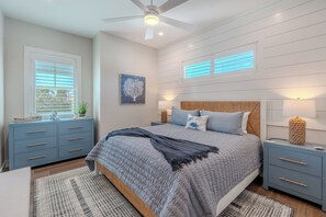 Ein Schlafzimmer mit Bett, Nachttischen, Deckenventilator und einem Fenster mit Jalousien.