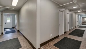 Een schone, moderne gang met houten vloeren, witte muren en meerdere deuren.