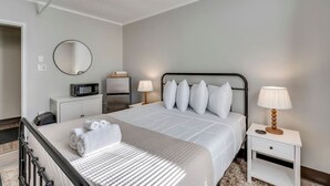 A hotel room with a bed, bedside tables, a microwave, a refrigerator, a round mirror, and a lamp. - The Pine Street Inn - Room 1 (Watertown)