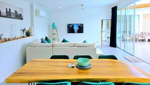 Un salon moderne avec un canapé, une table à manger en bois et un téléviseur fixé au mur.