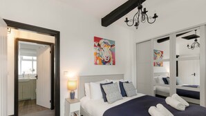 A hotel room with a bed, bedside lamp, artwork, and a mirror. - Period Cottage Settle (Settle)