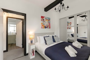 A hotel room with a bed, bedside lamp, artwork, and a mirror. - Period Cottage Settle (Settle)