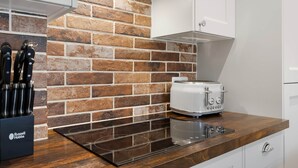 A kitchen with a brick backsplash, a toaster, and a knife block. - Period Cottage Settle (Settle)