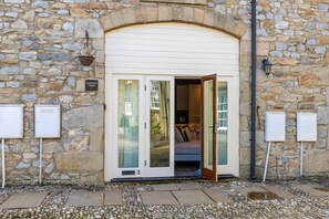A stone building with a white door, numbered 3, and a sign indicating 'Coachman's Cottage.' - Period Cottage Settle (Settle)