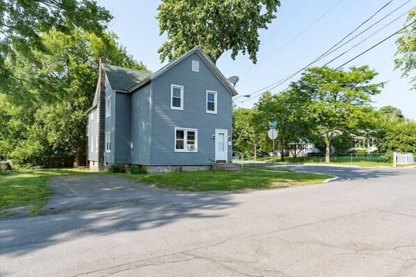 A two-story house with a gabled roof, a satellite dish, and a front yard with a sidewalk.