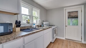 Une cuisine avec des meubles blancs, un plan de travail en granit, un four à micro-ondes, un évier et une cuisinière.