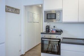 A compact kitchen with a microwave, oven, and a coffee maker on the countertop. - Perfect Escape for Two  (Civitanova Marche)
