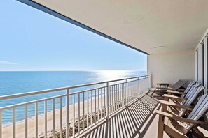 Un balcon avec vue sur l’océan, des chaises en bois et une balustrade.