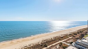 Uitzicht op de kust met een strand, een heldere lucht en een gebouw met een plat dak.