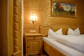 A wooden-paneled room with a bed, nightstand, and wall-mounted light fixture. - 1315 Alt Montafon Apartment 15 (Gaschurn)
