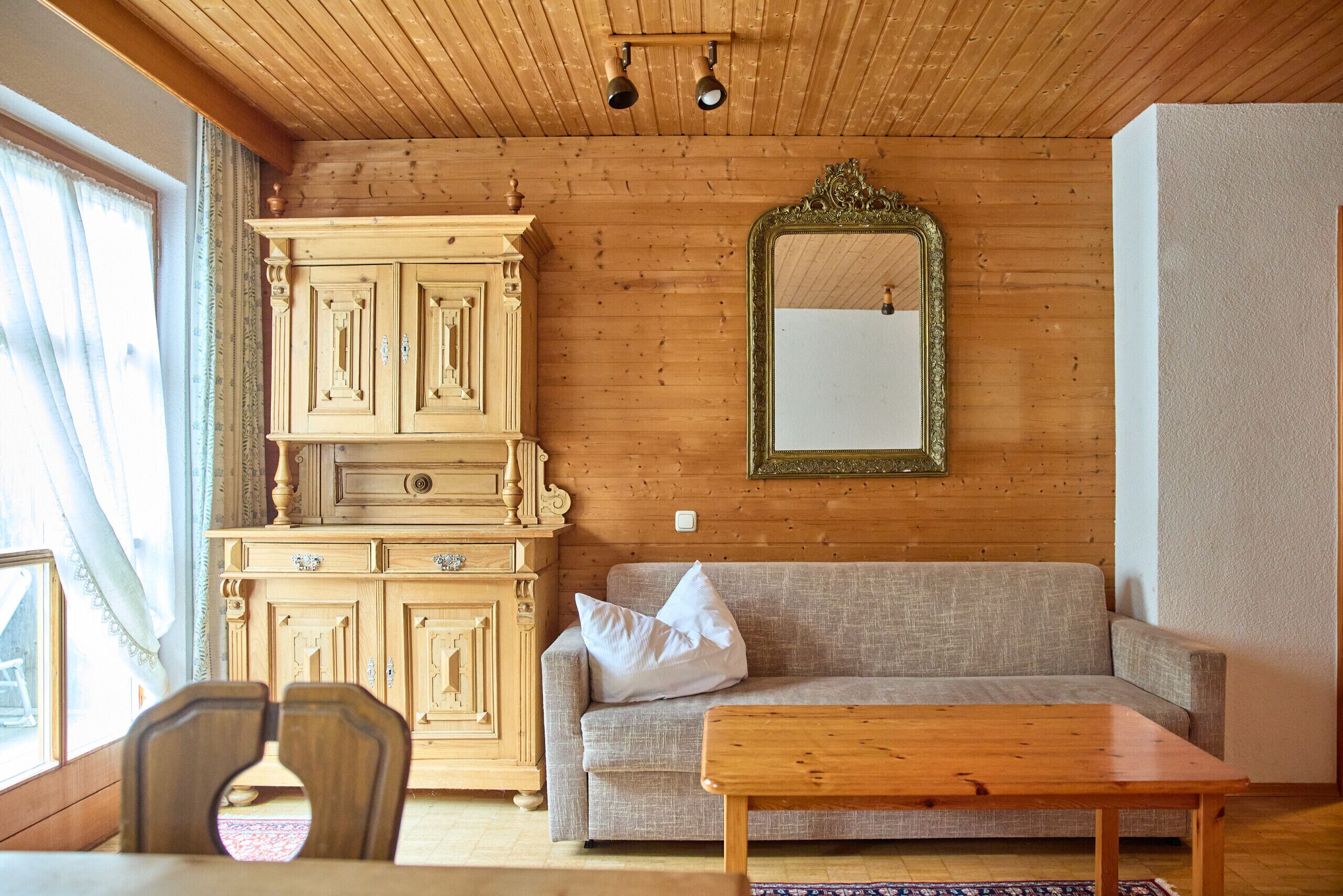 A wooden-paneled room with a sofa, a wooden table, and a cabinet.