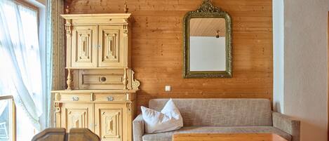 A wooden-paneled room with a sofa, a wooden table, and a cabinet.