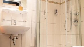 Un baño moderno con ducha de vidrio, bañera independiente y tocador con lavamanos y espejo.