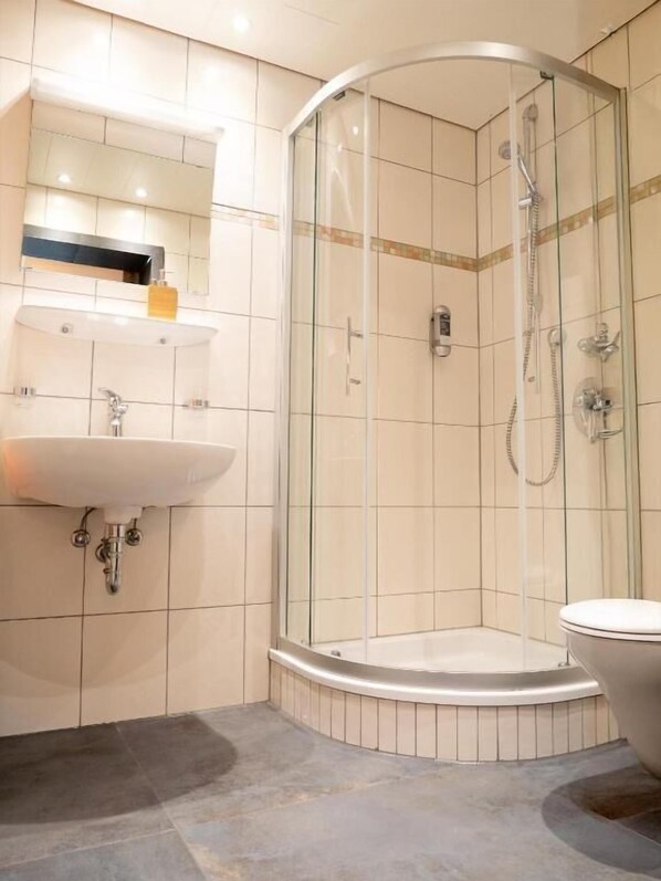 A modern bathroom with a glass-enclosed shower, a freestanding bathtub, and a vanity with a sink and mirror. - Pension Waldwinkel (Lenzkirch)