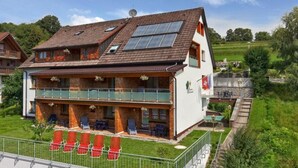 Un chalet de dos pisos con un balcón, comedor y jardín.