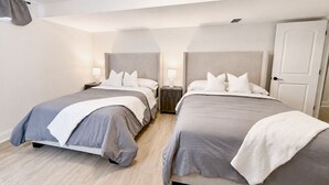 Een hotelkamer met twee bedden, een deur, een nachtkastje en een plafondlamp.