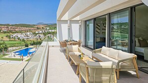 Ein Balkon mit Pool, Korbmöbeln und Blick auf eine Wohngegend.